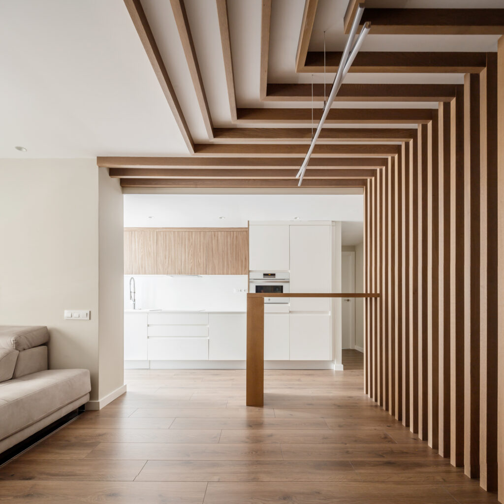 Salon diseño de Lidia Molia para vivienda en Valencia. Destaca el detalle de lamas de madera que salen del suelo hasta formar una estructura en el techo.