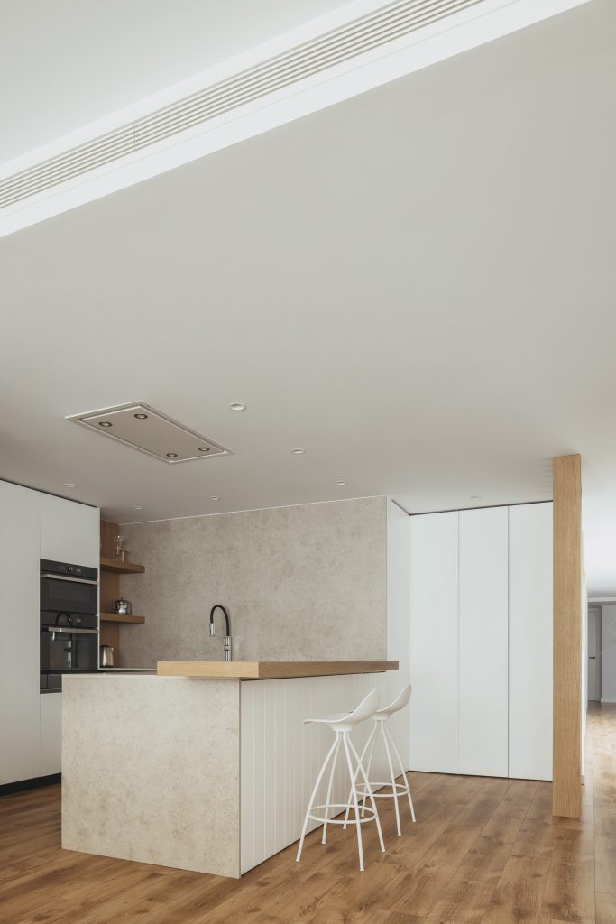cocina abierta con una peninsula revestida de porcelánico en tonos neutros 