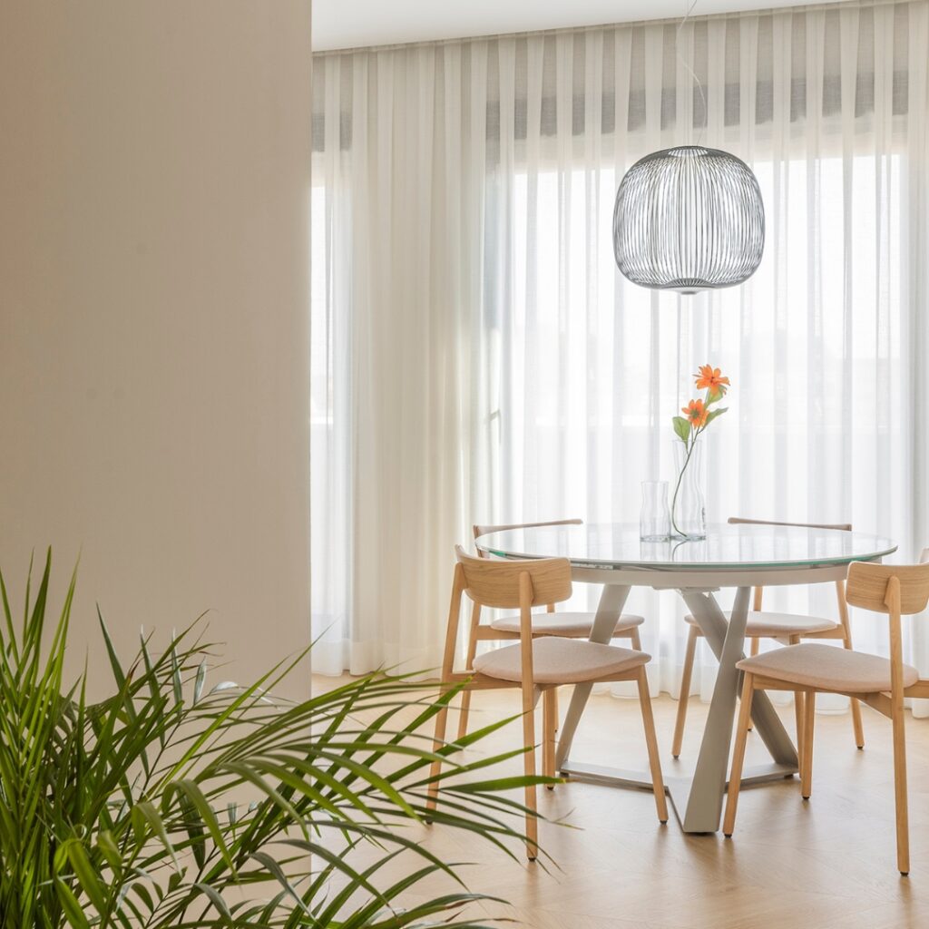 Mesa de comedor rodeada de sillas y un jarrón de flores, obra de Lidia Molina en Valencia.